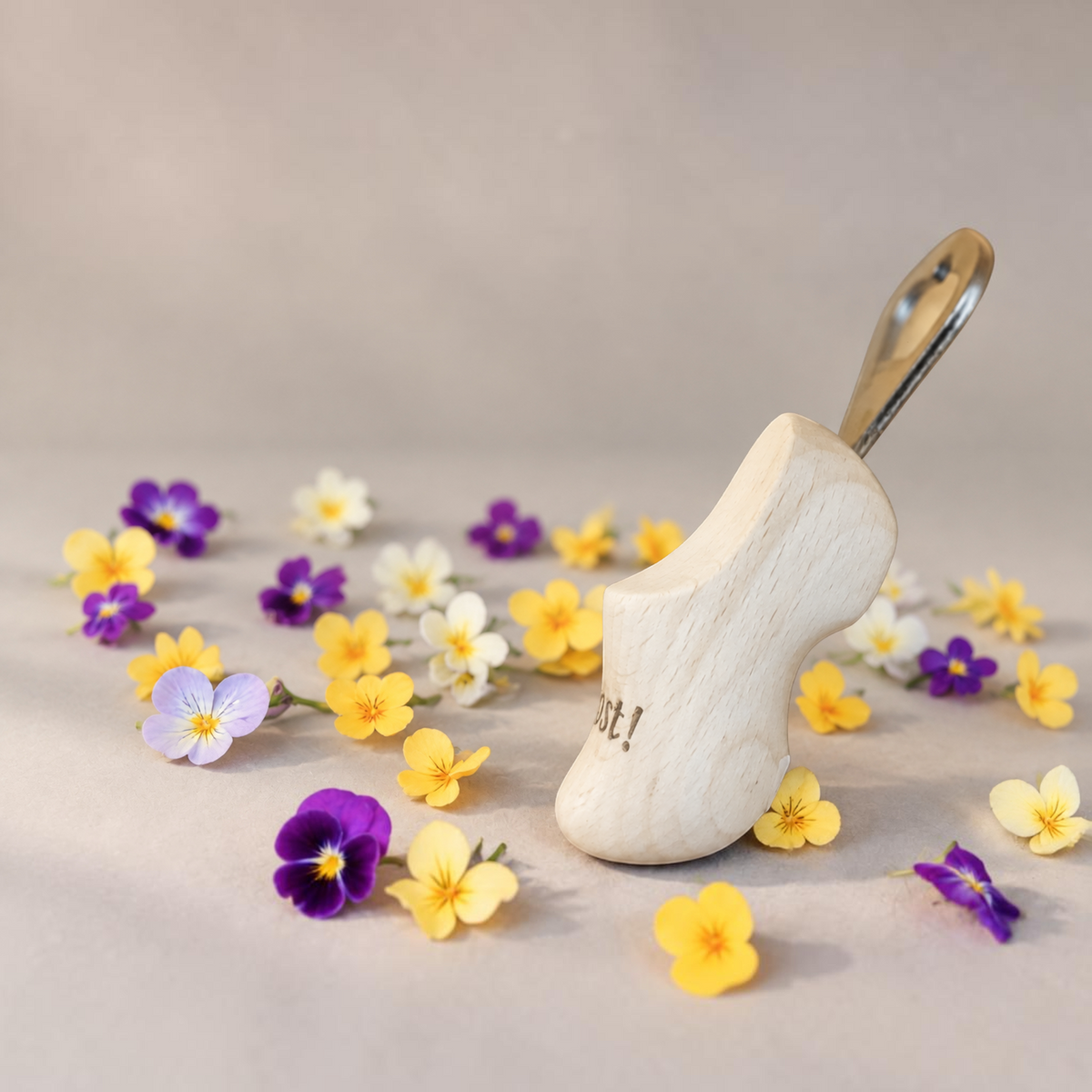 HUNTERLASE Flaschenöffner aus hellem Holz im traditionellen Holzschuh-Design, umgeben von bunten Stiefmütterchen.