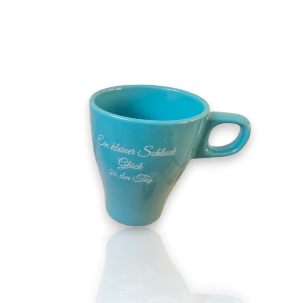 HUNTERLASE glänzend blaue Keramiktasse mit Aufdruck "Ein kleiner Schluck Glück für den Tag", auf Holzbrett mit Getreide.